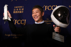 This file photo taken on October 9, 2018 shows Japanese billionaire Yusaku Maezawa, the first private passenger who will fly around the Moon aboard the SpaceX BFR launch vehicle, posing with a model rocket and space helmet prior to a press conference in Tokyo. It's the sort of chance that comes along just once in a blue Moon: a Japanese billionaire on March 3, 2021 is throwing open a private lunar expedition to eight participants from around the world.