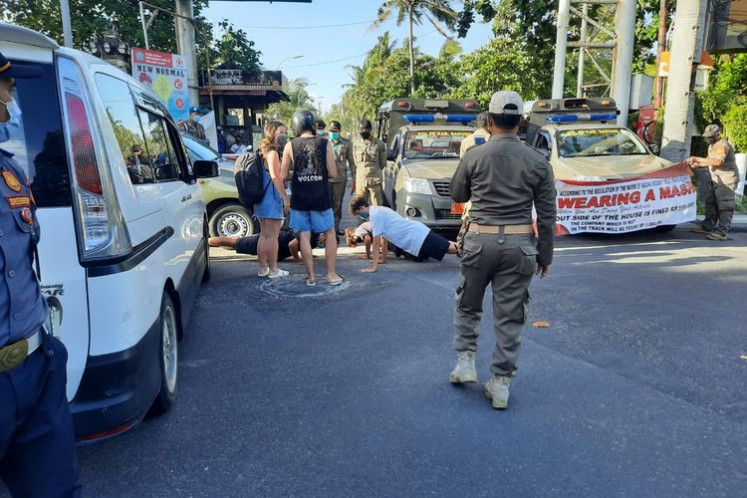Foreigners do push-ups as a punishment for not wearing masks at roadside security post in Bali. The Bali provincial administration also imposes a Rp 100,000 (US$7) fine on anyone caught not wearing a mask.