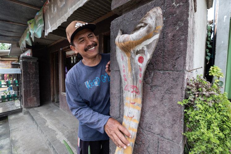 Sutikno with one of his Tetek Melek in front of his house. 