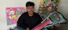 Excris Endy poses with a 'tetek melek' he made. During the height of demand for the traditional talismans last year, he became the main 'telek melek' maker in his hometown of Tulungagung.