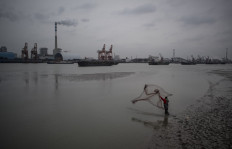 A man catches fish with a net in the Huangpu river across the Wujing Coal-Electricity Power Station in Shanghai on February 21, 2017 