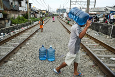 A man transports water "galon" (19-liter water container) to be distributed to residents in the Kampung Muka in Ancol, North Jakarta, on March 21, 2017.