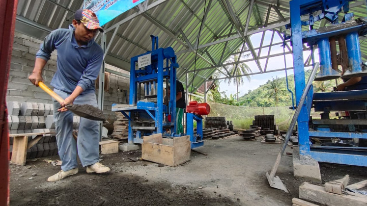 A villager puts cement in a brick-making machine in Sanenrejo village, Jember regency, East Java on Feb. 15, 2021. Once home to dozens of illegal loggers, the villagers have shifted its attention to alternate sources of income, such as making concrete brick or 'batako' that is sold Rp 1,800 (US 13 cents) each.
