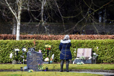 A woman stands at the gravestone of teacher Gwen Mayor in the memorial garden where the victims of the Dunblane School Shooting on March 12.