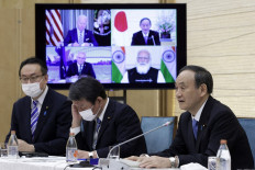 Japan's Prime Minister Yoshihide Suga (right) speaks next to a monitor displaying the virtual meeting with US President Joe Biden (top left), Australia's Prime Minister Scott Morrison (bottom left) and India's Prime Minister Narendra Modi during the virtual Quadrilateral Security Dialogue (Quad) meeting, at his official residence in Tokyo on March 12, 2021.
