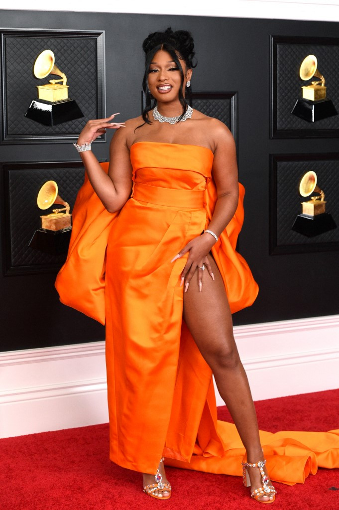 Singer Megan Thee Stallion in a bright orange strapless Dolce & Gabbana gown with a high leg slit, a dramatic bow on the back -- and tons of diamonds.