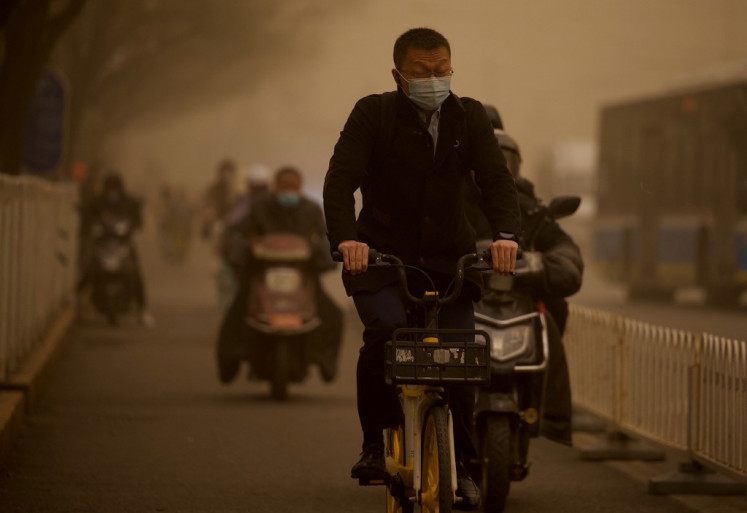 People commute along a street during a sandstorm in Beijing on March 15, 2021.
 (Agence France Presse/Noel Celis ).
Usage: 0