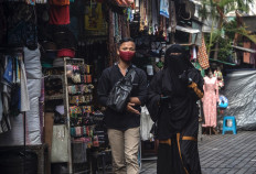 This picture taken on March 17 shows a man walking with his wife wearing a full face covering, or niqab, while shopping at a market in Surabaya. Schoolgirls, female teachers and other civil servants across Indonesia are often forced or pressured to wear Islamic head coverings, sometimes including Christians and other non-Muslim minorities, said a report published on March 18 by Human Rights Watch (HRW).