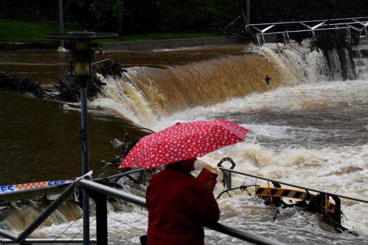 A woman takes pictures of the overflowing Parramatta river in Sydney on March 22, 2021 as Sydney braced for its worst flooding in decades after record rainfall caused its largest dam to overflow and as deluges prompted mandatory mass evacuation orders along Australia's east coast. 