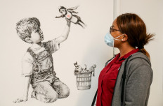 A handout picture received from University Hospital Southampton on May 7, 2020 shows a member of staff posing with an artwork by street artist Banksy.  