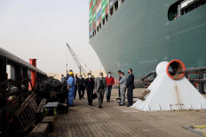 A handout picture released by the Suez Canal Authority on March 25, 2021 shows an Egyptian officials checking the operation trying to free Taiwan-owned cargo MV Ever Given (Evergreen), a 400-metre- (1,300-foot-)long and 59-metre wide vessel, lodged sideways and impeding all traffic across the waterway of Egypt's Suez Canal. Egypt's Suez Canal Authority said it was 