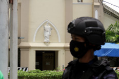 A police officer stands guard in front of the Makassar Catholic Cathedral in South Sulawesi on Monday. The previous day, two suicide bombers detonated a bomb in the church's courtyard, killing them and injuring at least 19 churchgoers and church officials.