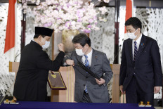 Japanese Foreign Minister Toshimitsu Motegi (center) and Indonesian Defense Minister Prabowo Subianto (left) elbow-bump as Japanese Defense Minister Kishi Nobuo looks on at the signing of a defense agreement in Tokyo on Tuesday.
