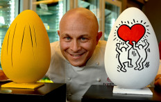 Pastry chef Walter Musco poses for pictures with Easter chocolate eggs painted like the "Tagli" painting by Argentine-Italian artist Lucio Fontana (L) and like a painting of US artist Keith Haring in order to pay them a tribute, in his pastry shop "Pasticceria Bompiani", in Rome on March 30, 2021. Each egg is carved as a tribute to an artist chosen by Walter Musso. "The idea is very simple, I have a great passion for art, and then I broadened my scope in literature, music and cinema. All the artists present in this exhibition represent ten years of production and they are the most representative and those that I like the most" explaines the pastry chef.