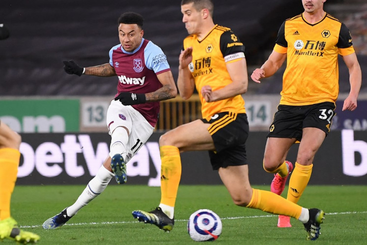 West Ham United's English midfielder Jesse Lingard (L) has an unsuccessful shot during the English Premier League football match between Wolverhampton Wanderers and West Ham United at the Molineux stadium in Wolverhampton, central England on April 5, 2021.