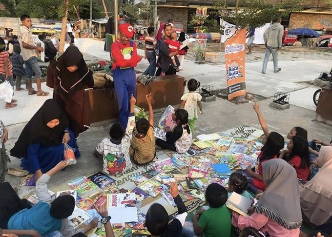 Adi Sarwono (in red shirt and cap), tutors children in Lampung as part of the activities he provides through his Busa Pustaka mobile library. Relying on some Twitter 