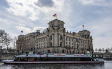 A river cruise ship sporting a banner reading: "Workable solutions instead of endless loops" sails past the Reichstag building which houses the Bundestag lower house of parliament, on the river Spree, during a protest by tourist ship operators who have had to cease operations, amid a Coronavirus (Covid-19) pandemic in Berlin, on April 9, 2021. 