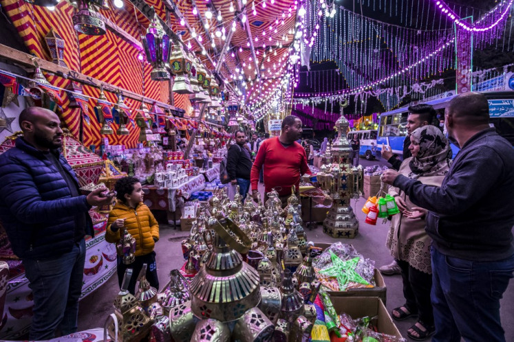 People shop from a stall selling Ramadan lanterns along a main street in the in the northern suburb of Shubra (home to a large Christian population) of Egypt's capital Cairo on April 12, 2021, at the start of the Muslim holy fasting month of Ramadan. 