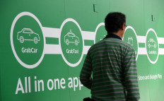 A man walk past the Grab transport office in Singapore on June 13, 2018. Toyota said on June 13, it was investing 1 billion US dollars in Asia ride-share company Grab, as the Japanese automaker looks to expand beyond its core business into the 