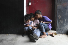Children play on a cell phone at a market in New Delhi on September 23, 2019. 