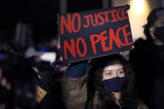 A demonstrator holds up a sign during a protest outside the Brooklyn Center police station on April 17, 2021 in Brooklyn Center, Minnesota. This is the seventh day of protests in the suburban Minneapolis city following the fatal shooting of 20-year-old Daunte Wright by Brooklyn Center police officer Kimberly Potter, who has since resigned from the force and today was charged with second-degree manslaughter. 