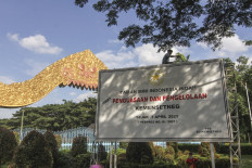 A worker installs a sign announcing the State Secretary's takeover of Taman Mini Indonesia Indah (TMII) cultural park in front of the park's gate in East Jakarta on April 7. The government has taken over the management of the cultural park from Harapan Kita Foundation, which had managed the park for decades.
