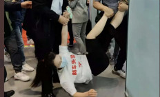 A screen grab from a viral video showing a woman in Shanghai being dragged away from a Tesla exhibition.