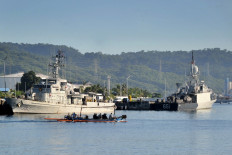 An outrigger canoe sails past Indonesian Navy ships at the naval base in Banyuwangi, East Java province, on April 24, 2021, as the military continues search operations off the coast of Bali for the Navy's KRI Nanggala submarine that went missing April 21 during a training exercise. 
