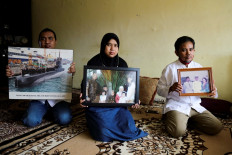 Family members hold photographs of Marine Colonel Harry Setiawan, commander of the Navy's KRI Nanggala (402) submarine that went missing off the coast of Bali on April 21 during a training exercise, at their family home in Depok on April 24, 2021. 