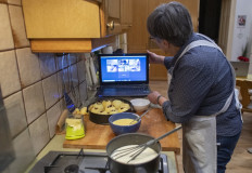 Karin Hofbauer, 62, grandmother and member of the social enterprise Vollpension, adjusts the screen of a laptop as she gives an online baking class in the kitchen of her home in Vienna, Austria, on March 12, 2021. Vollpension is a social enterprise where retirees bolster their often meagre state pensions. The online baking courses' success with hundreds of participants is now prompting Vollpension to go global.