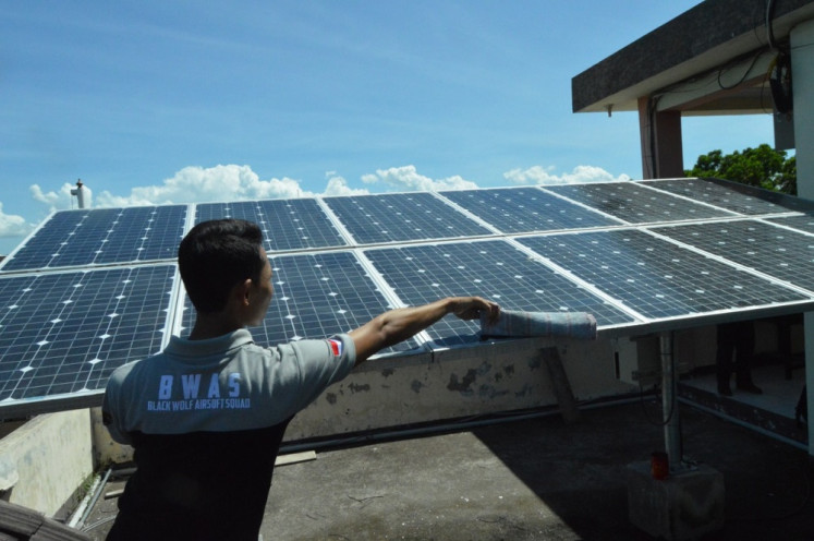 A technician cleans a photovoltaic panel at state vocational school SMK 3 in Mataram, West Nusa Tenggara, in April 2021.