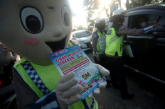 A costumed police officer displays a leaflet discouraging people from participating in the Idul Fitri tradition of mudik (exodus) because of the risk of COVID-19 contagion, in Tegal, Central Java, on April 26.