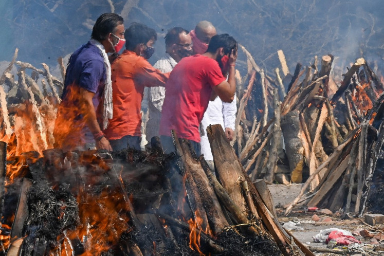 A man reacts as he performs the last rites of his relative amid the funeral pyres of victims who died of the Covid-19 coronavirus during mass cremation held at a crematorium in New Delhi on April 27, 2021. 