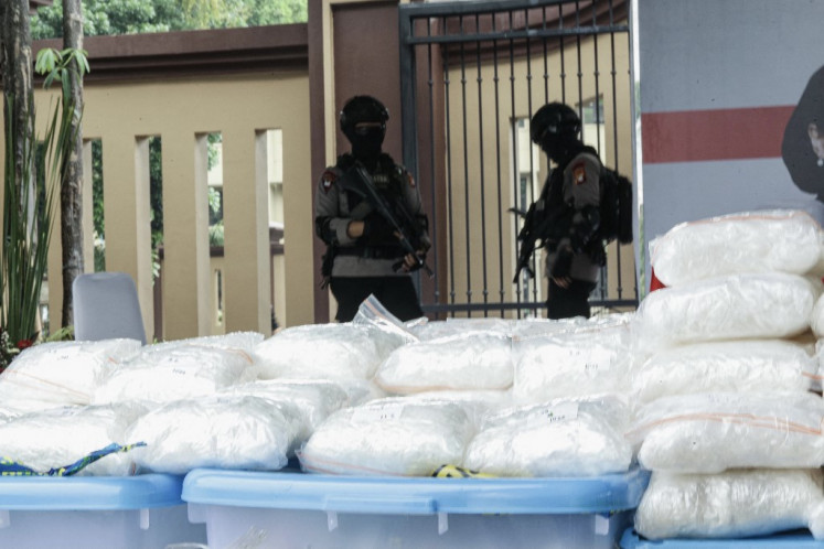 Police officers guard a cache of methamphetamine during a press conference in Jakarta on April 28, 2021. The drug was seized during a raid on a smuggling ring that trafficked 2,267 kilograms of methamphetamine, worth around US$82 million, from Afghanistan.
