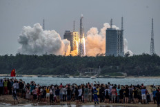 People watch a Long March 5B rocket, carrying China's Tianhe space station core module, as it lifts off from the Wenchang Space Launch Center in southern China's Hainan province on April 29, 2021. 