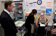 Anne Hyslop (right) speaks with practice nurse Youri Park (center) after receiving an AstraZeneca vaccine while Australian Health Minister Greg Hunt (left) looks on in Melbourne on April, 7, 2021 as Australia's prime minister Scott Morrison blamed restricted vaccine supply from Europe for his country's halting coronavirus inoculation efforts, as he faced down growing public frustration over the sluggish rollout. 