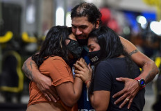 Covid-19 survivor Raul Gutierrez -who spent several months in an intensive care unit of an Argentinian hospital- hugs his daughters at his gym in Lanus, Buenos Aires province, Argentina, on April 21, 2021.
