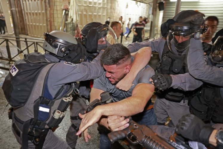 Israeli security forces scuffle with a Palestinian protester outside the Damascus Gate in Jerusalem's Old City on May 9, 2021. Israel vowed to restore order in Jerusalem after hundreds of Palestinian protesters were wounded in a weekend of clashes with Israeli security forces, as a key court hearing on a flashpoint property dispute was postponed.