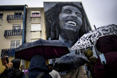 In this file photo taken on November 17, 2019 Visitors watch a mural by Portuguese artist Odeith depicting Jamaican singer Bob Marley during a guided visit to Quinta do Mocho neighbourhood in Sacavem, outskirts of Lisbon. It's been four decades since Bob Marley's death, a period longer than the reggae icon's brief but potent life that skin cancer ended when he was 36. 