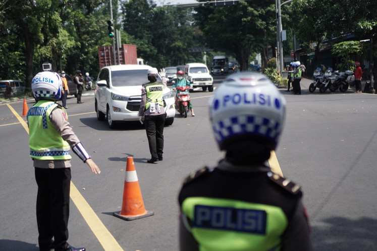 Police officers stop a vehicle with a license plate from another city in Surakarta, Central Java on Tuesday. Joint security personnel of the police, military and public order agency (Satpol PP) in Surakarta has tightened checkpoints on roads leading into the city ahead of the Idul Fitri holiday as the government restricts all 'mudik' (exodus) trips to prevent COVID-19 transmission.
