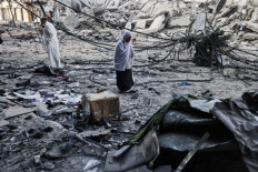 Palestinians walk after performing Eid al-Fitr prayers amidst debris near the al-Sharouk tower, which housed the bureau of the Al-Aqsa television channel in the Hamas-controlled Gaza Strip, after it was destroyed by an Israeli air strike, in Gaza City, on May 13, 2021. Israel faced an escalating conflict on two fronts, scrambling to quell riots between Arabs and Jews on its own streets after days of exchanging deadly fire with Palestinian militants in Gaza.