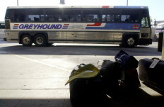 In this file photo taken on October 3, 2001 an empty Greyhound bus pulls into the Greyhound Bus Terminal as luggage sits on the curb in Detroit after Greyhound suspended bus service. After almost a century, North America's largest motorcoach operator Greyhound announced Thursday it is shutting down all of its remaining intercity bus routes in Canada, blaming the pandemic for a sharp drop in its already dwindling ridership.