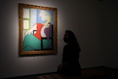 In this file photo taken on April 22, 2021 a gallery worker poses alongside an artwork titled 'Femme assise près d'une fenêtre (Marie-Thérèse)' by Spanish painter Pablo Picasso during a photocall at Christie’s auction house in central London. Pablo Picasso's 