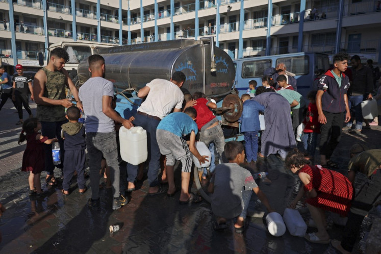 Palestinians who fled their home due to Israeli air and artillery strikes fill jerrycans with water at a school hosting refugees in Gaza city, on May 14, 2021, as cross-border violence between the Israeli military and Palestinian militants continues in the Gaza Strip. 