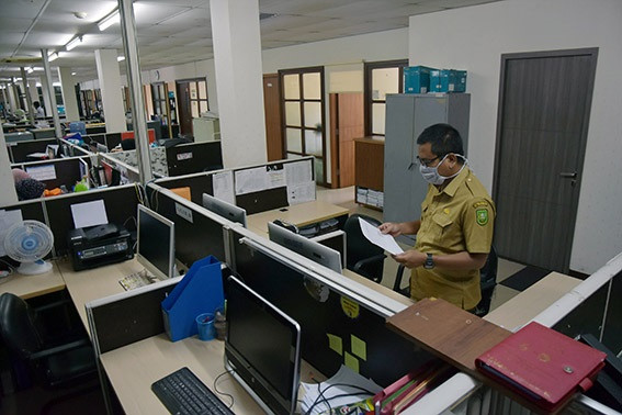 Remote work: A civil servant works during his in-office shift at the Riau Communication, Information and Statistics Agency in Pekanbaru on April 20, 2020, as his colleagues work from home.