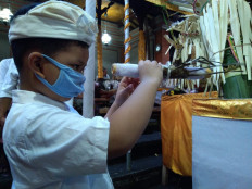 Soul searcher: A boy uses a traditional contraption made of bamboo that is believed to allow loved ones of the deceased to see the latter's soul. The picture was taken during the Hindu funeral of Ida Pedande Putu Peling Umur, 93, in Ubud, Bali, on March 19.