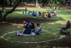 Visitors sit in circles to keep their distance from others at Ragunan Zoo in South Jakarta on May 14, 2021. The Jakarta administration opened several public parks and tourist destinations across the capital at 30 percent capacity and with limited opening hours during the 2021 Idul Fitri holiday season.