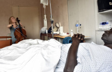 French musician and art therapist Claire Oppert, plays music for a patient at an intensive care unit of the Sainte Perine hospital on July 11, 2016, in Paris.
