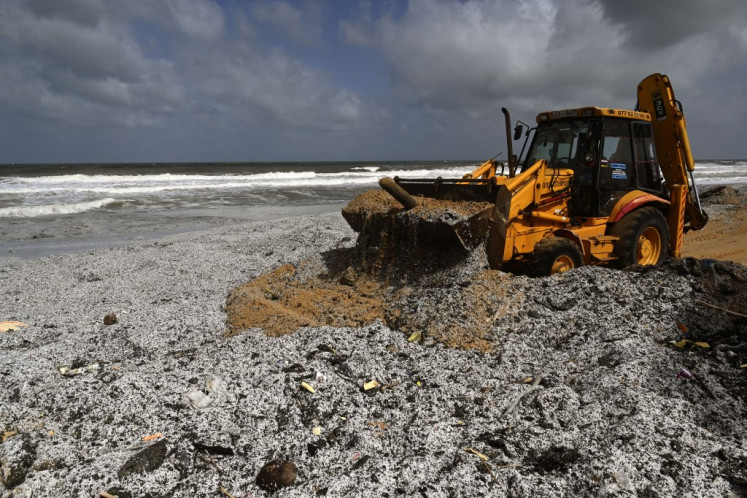 An earthmover works to remove debris washed ashore from the Singapore-registered container ship MV X-Press Pearl, which has been burning for the ninth consecutive day in the sea off Sri Lanka's Colombo Harbour, on a beach in Colombo on May 28, 2021. 