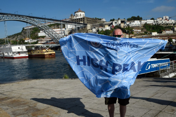 A Manchester City supporter poses with a flag at Ribeira in Porto on May 28, 2021 on the eve of UEFA Champions League final football match between Manchester United and Chelsea at the Dragao stadium.